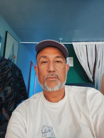 Jarrett in a white shirt and hat against a blue background